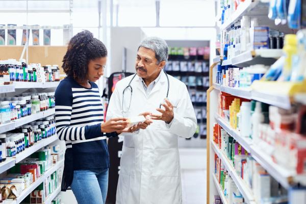 A pharmacist helps a young lady at a drug store