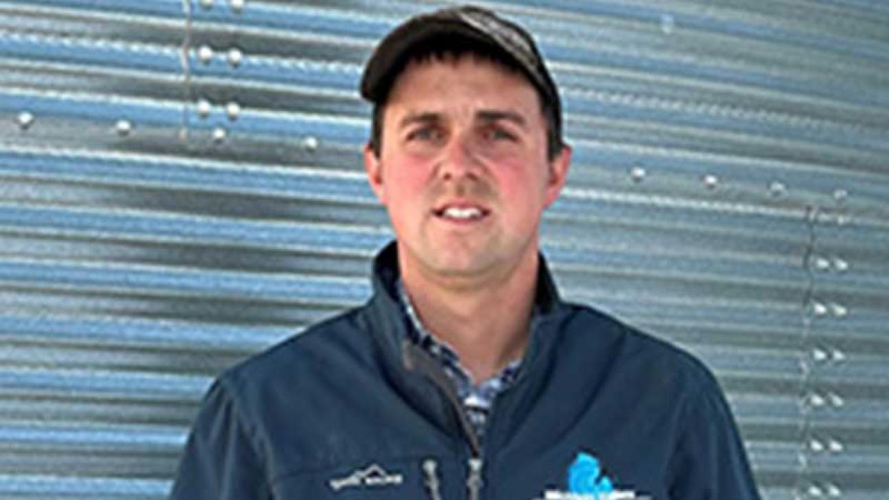 Portrait of a mail young farmer looking at the camera while standing in front of a wall covered with corrugated aluminum.