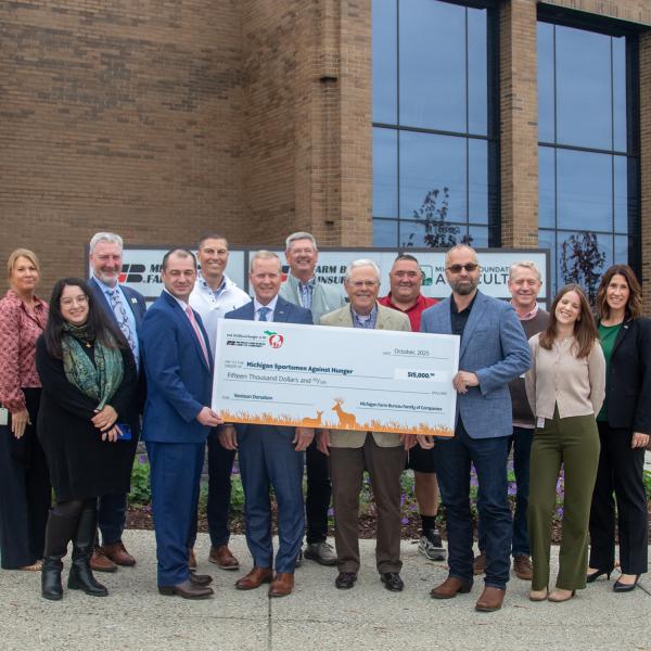 Portrait of the MFB Venison Donation Task Force smiling at the camera while holding a large novelty donation check.