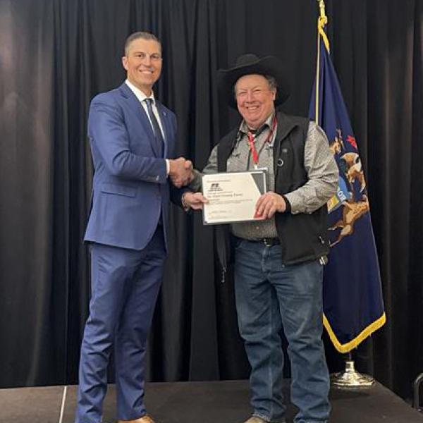 Ben LaCross presenting a county Farm Bureau president with a 2026 Champions of Excellence Award.