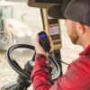 A farmer speaking into a hand-held radio while sitting in the cab of a tractor.